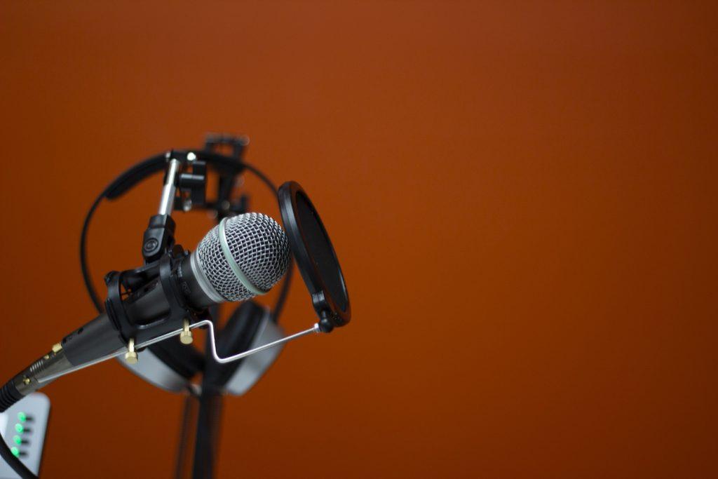 Closeup of podcasting microphone against orange background