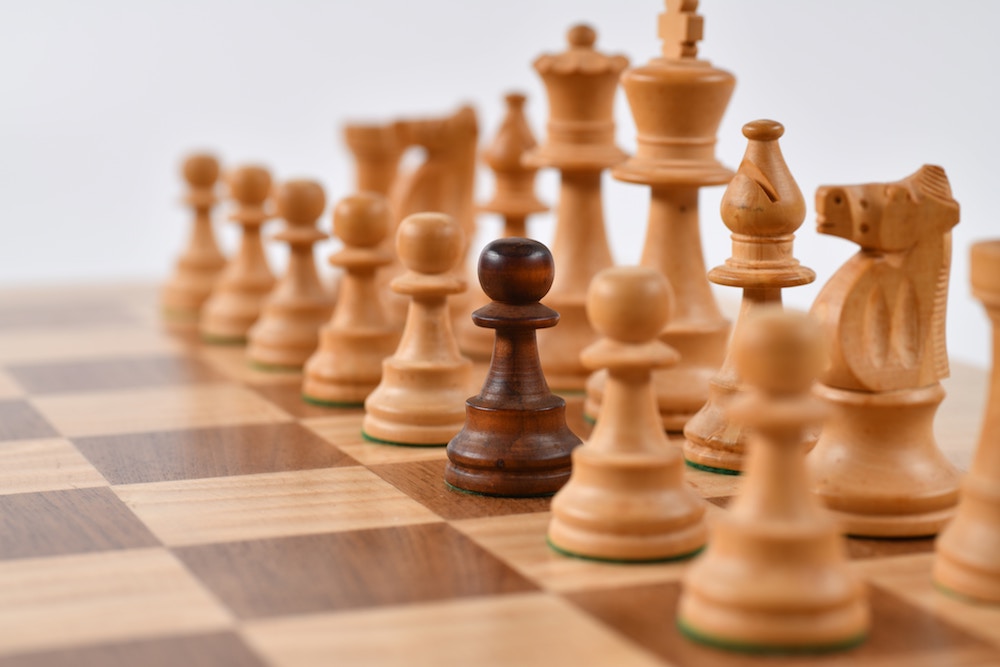White wooden chess pieces with one black pawn