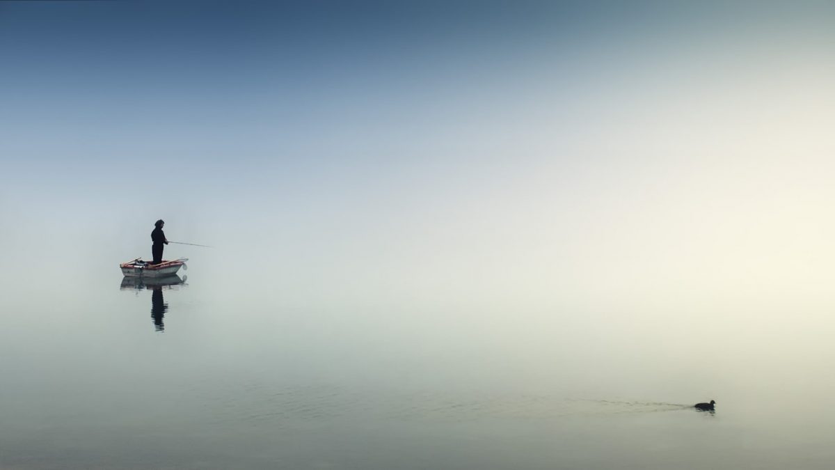 Person standing on a boat in the middle of an empty lake