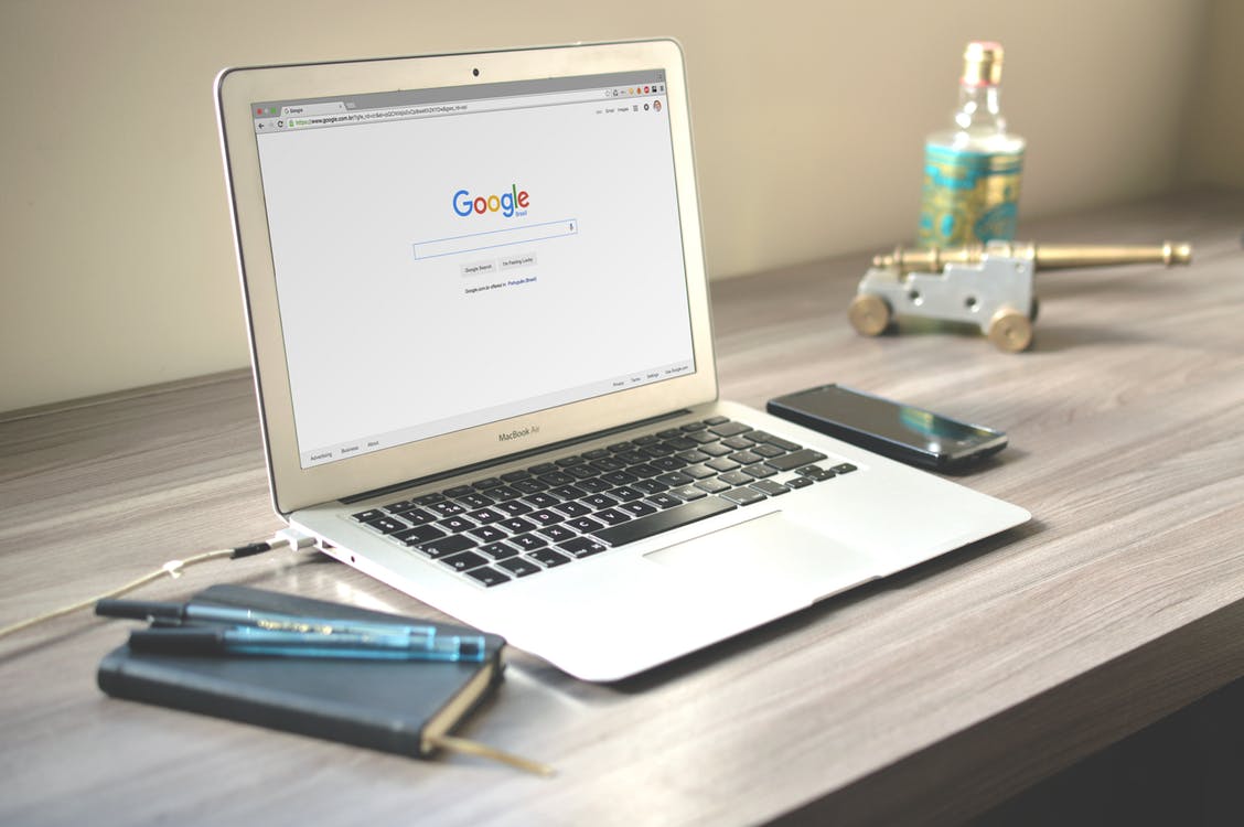 Notebook and pens next to an open Mac on Google