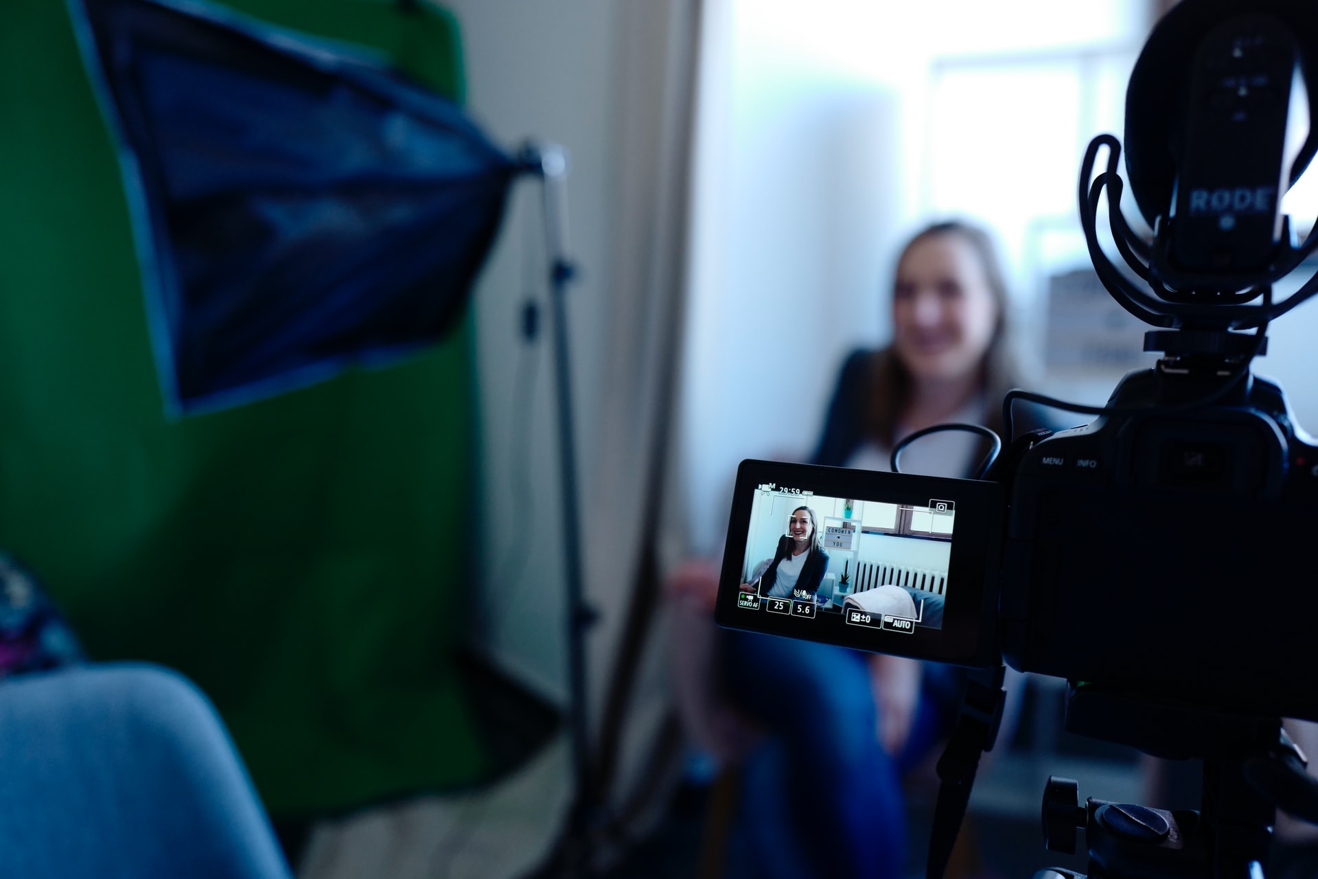 Person sitting in front of a camera. Focus is on the viewfinder of the camera.